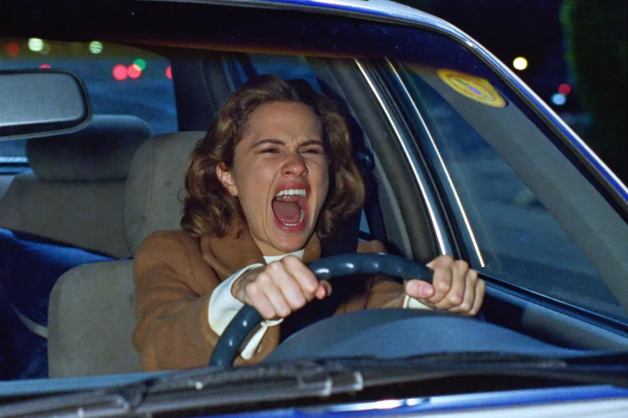 A woman screams at the wheel of her car at night