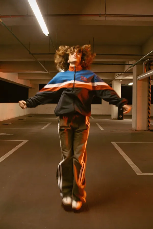 A dancer mid-jump in an orange-lit parking garage