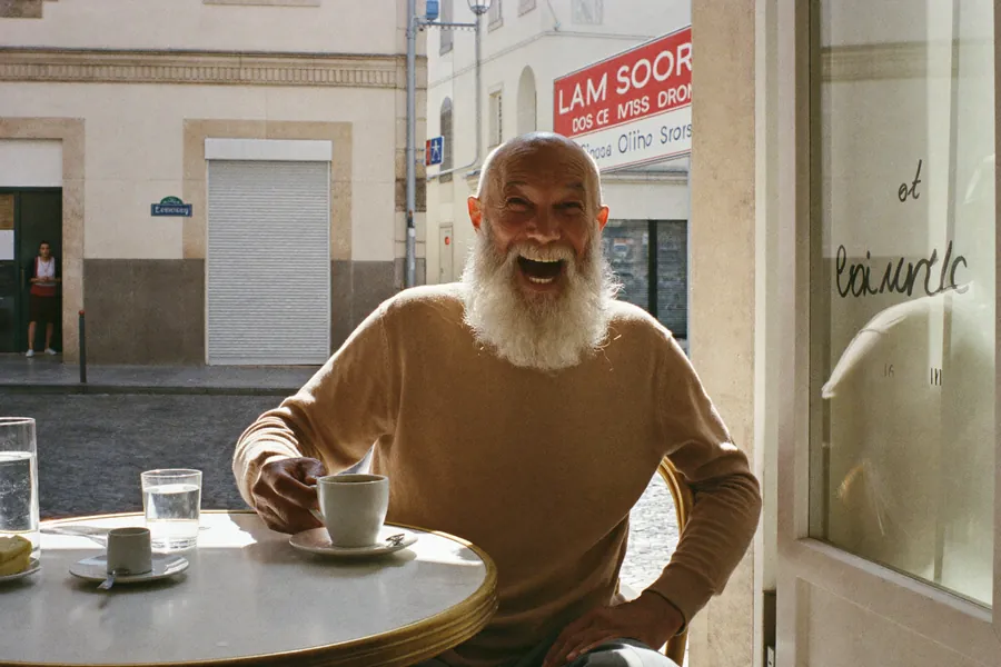 An older man laughing at a Lisbon cafe table