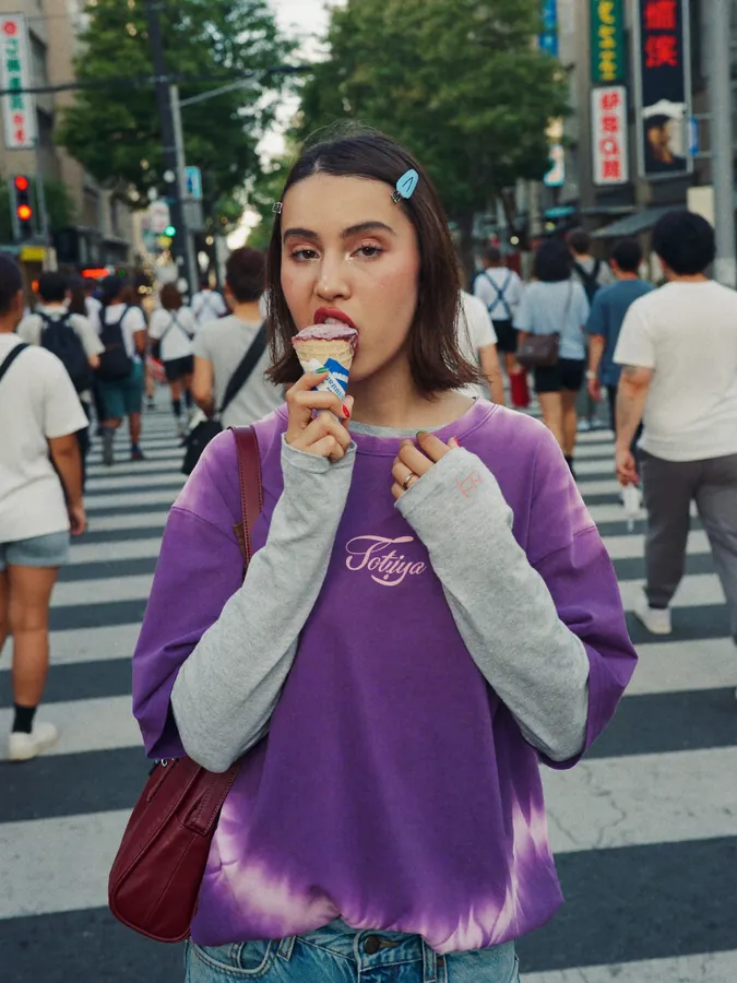 A young woman eating ice cream in a busy Tokyo crossing